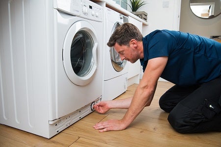 Domestic & General engineer kneeling by a washing machine